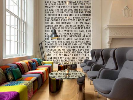 The image shows a trendy lounge with vibrant, multi-colored sofas on the left and modern gray armchairs on the right. Text covers the back wall.